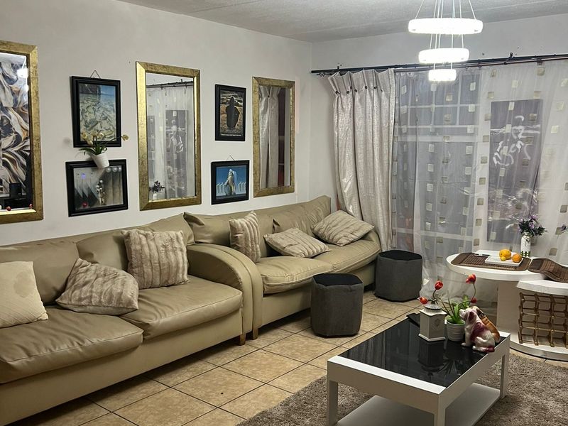 A living room featuring ceramic floor tiles, a modern pendant light fixture, and a sliding glass door with curtain treatments.