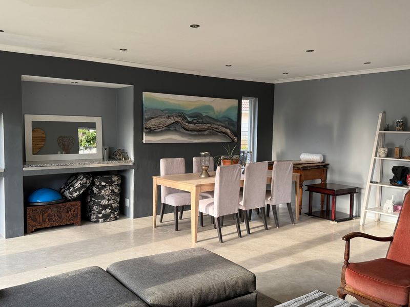 Spacious open-plan living and dining area featuring polished concrete floors, recessed downlighting, and a built-in alcove for storage or display.