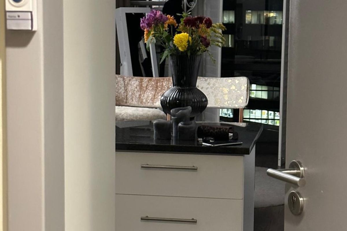 A view through a doorway into a kitchen area featuring a central island with stone countertop and modern drawer cabinetry.
