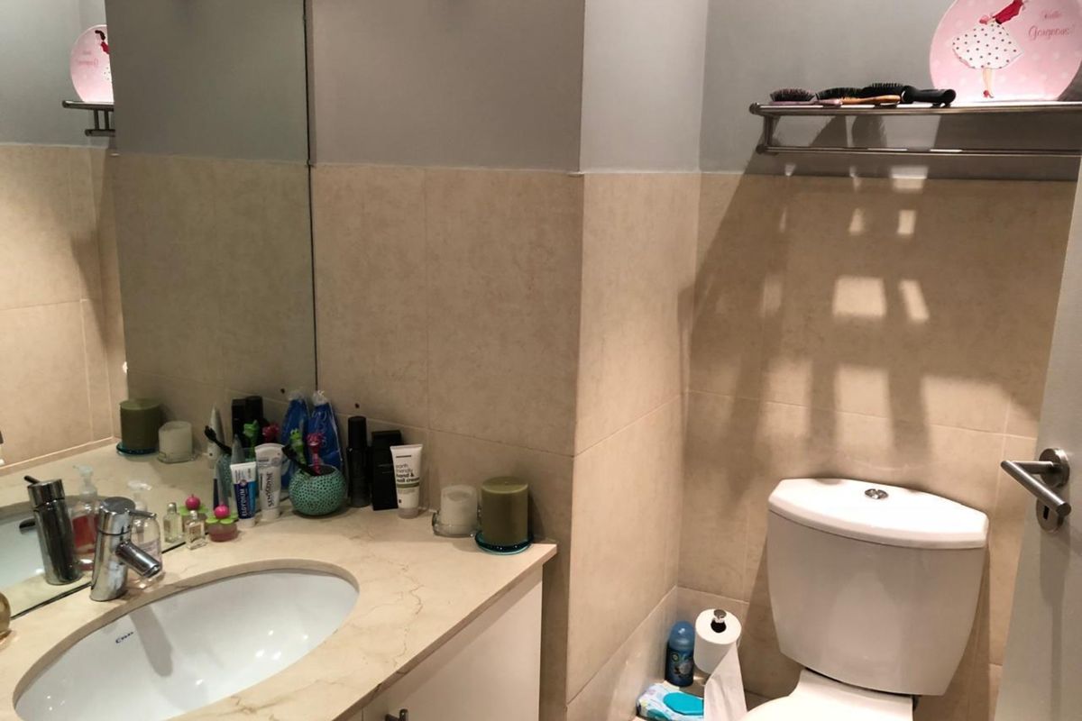A functional bathroom featuring a vanity with integrated basin, wall-mounted mirror, and a standard toilet with tiled wall finishes.