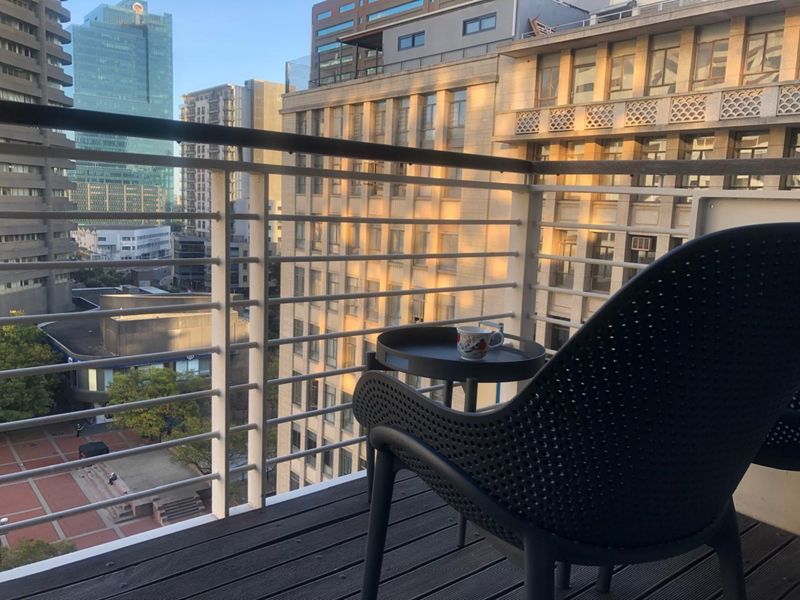 A private balcony featuring modern metal balustrades and decking, offering an elevated urban view of the surrounding city architecture.