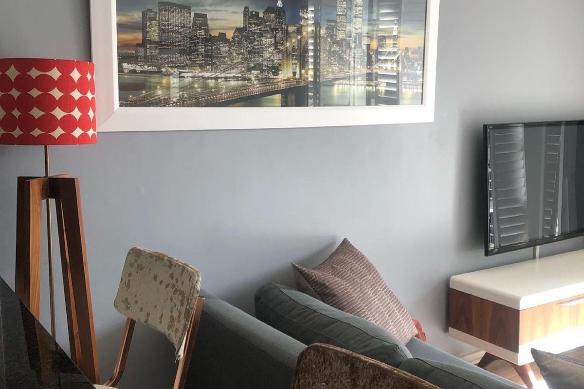 A living room area featuring a wall-mounted television and neutral grey wall finishes.