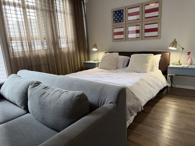 A well-maintained bedroom featuring laminate flooring and a large window with natural light, providing a comfortable and functional living space.