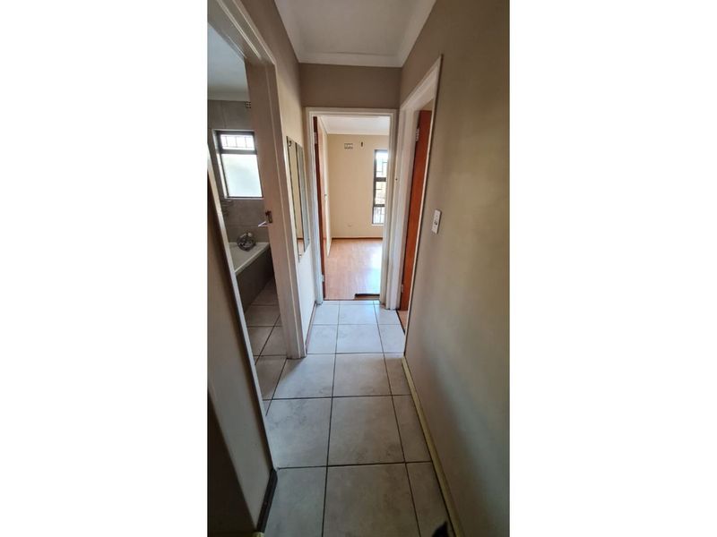 A functional hallway with tiled flooring providing access to adjacent rooms, including a bathroom and bedroom.