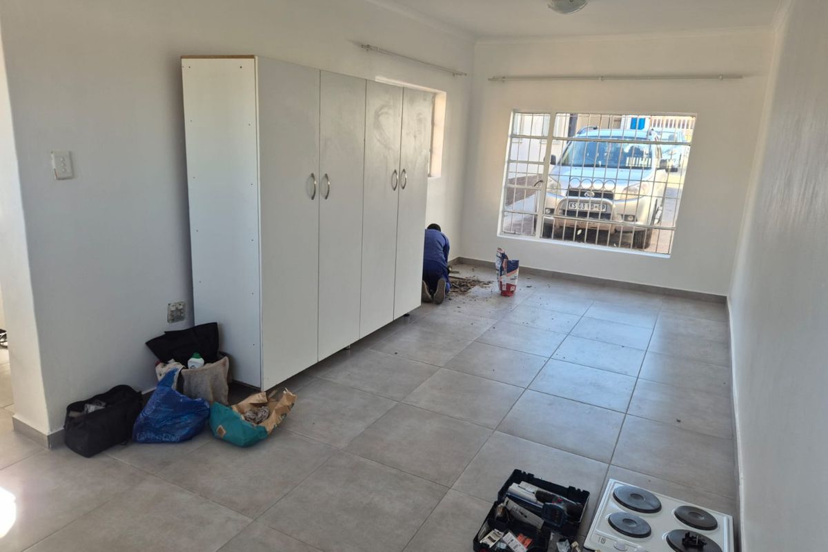 A bedroom featuring tiled flooring and built-in cupboards, currently undergoing minor maintenance and finishing work.