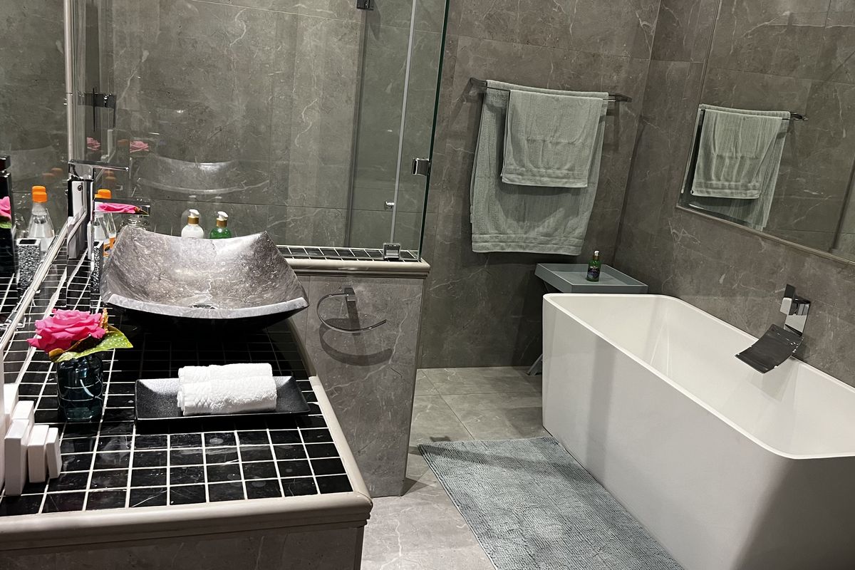 Modern bathroom featuring a freestanding bathtub, glass-enclosed shower, and a unique vessel sink set on a tiled vanity.