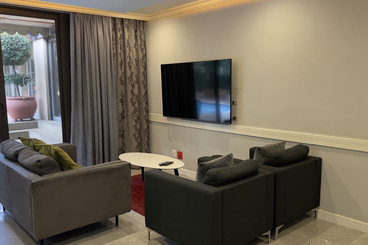 A comfortable living room featuring tiled floors, chair rail molding, recessed lighting, and a large sliding glass door providing access to an outdoor patio area.