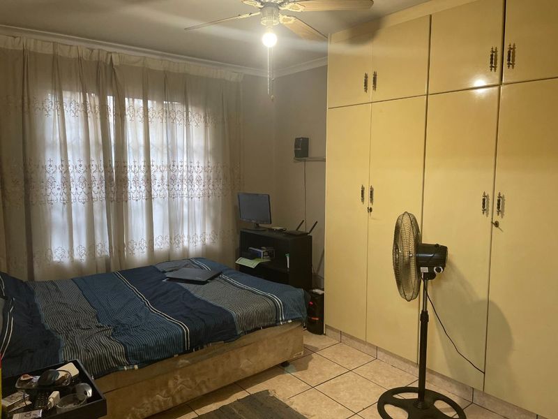A bedroom featuring tiled flooring, a ceiling fan, and built-in cupboards providing ample storage space.
