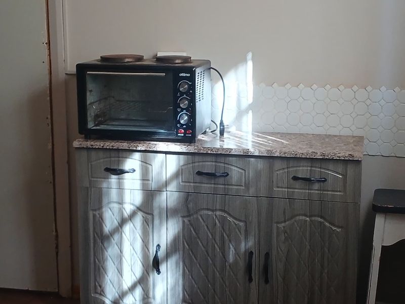 A compact kitchen area featuring built-in cabinetry with a granite countertop and a decorative hexagonal tile backsplash.