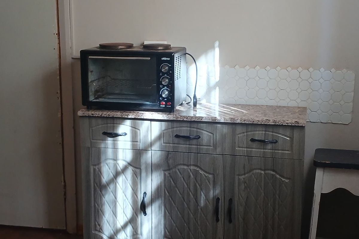 A compact kitchen area featuring built-in cabinetry with a granite countertop and a decorative hexagonal tile backsplash.