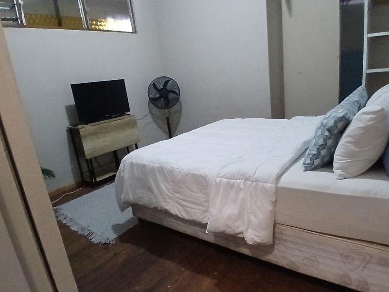 A bedroom featuring hardwood flooring and built-in shelving, providing a functional space with neutral wall finishes.