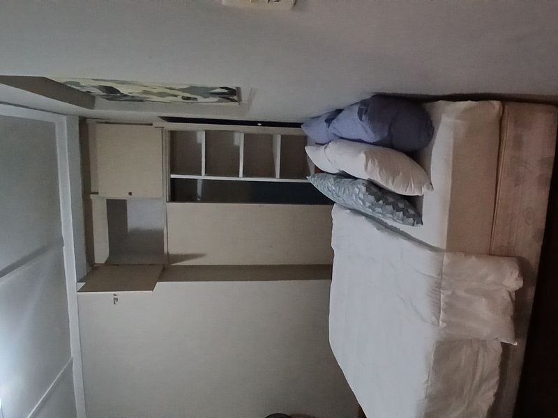 A bedroom featuring built-in wardrobe and shelving units with timber flooring.