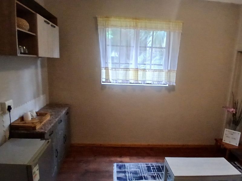 A compact kitchen area featuring built-in cabinetry, laminate countertops, and a window with natural light.