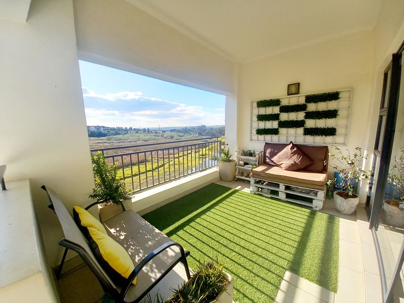 A covered balcony featuring tiled flooring and a metal balustrade, offering scenic views of the surrounding landscape.