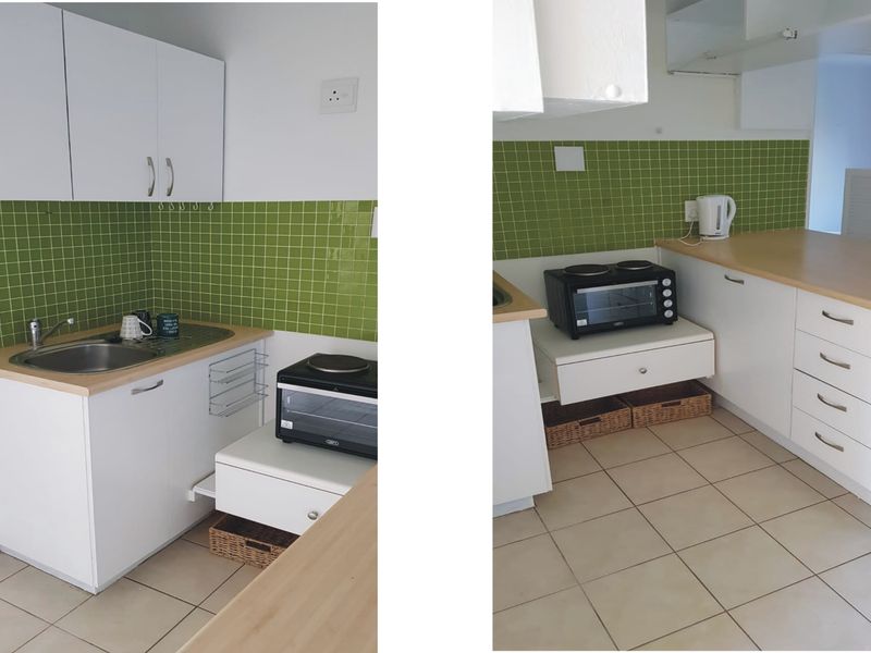 A compact kitchen featuring white cabinetry, laminate countertops, and a green tiled backsplash with tiled flooring.