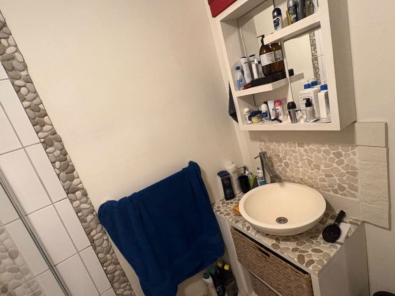 Bathroom featuring a vessel sink with pebble tile backsplash, built-in medicine cabinet, and a shower enclosure.