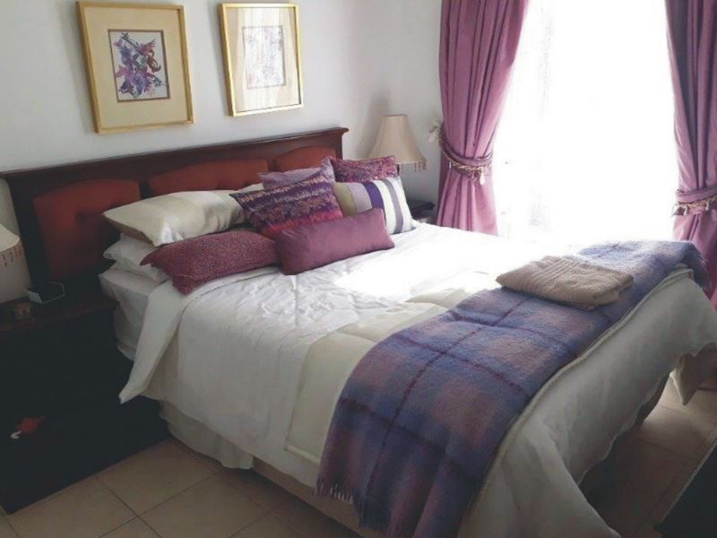 A cozy bedroom featuring tiled flooring and natural light from the window.