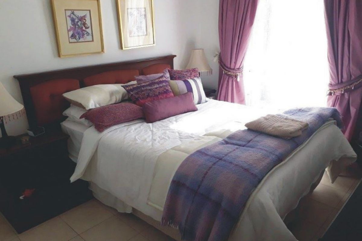 A cozy bedroom featuring tiled flooring and natural light from the window.