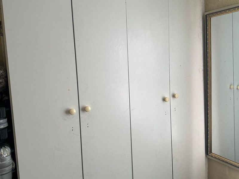 Bedroom featuring a full-height built-in wardrobe with white doors and a wall-mounted mirror.