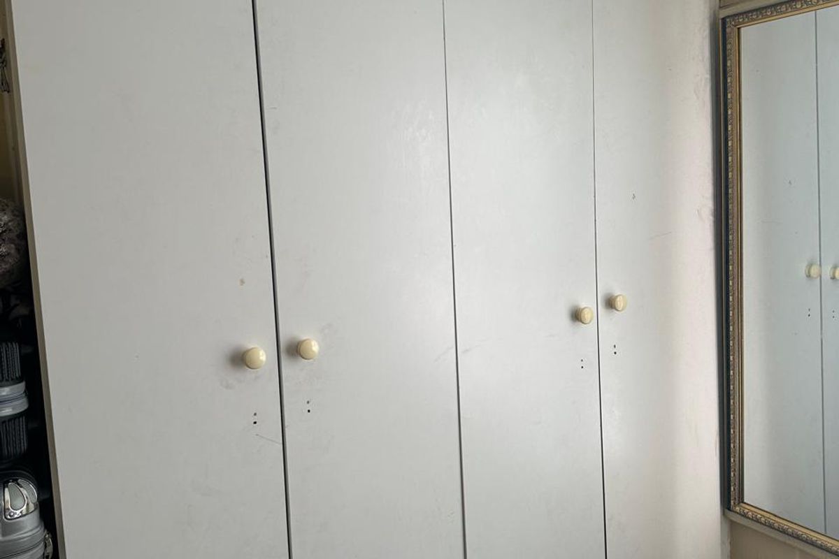 Bedroom featuring a full-height built-in wardrobe with white doors and a wall-mounted mirror.