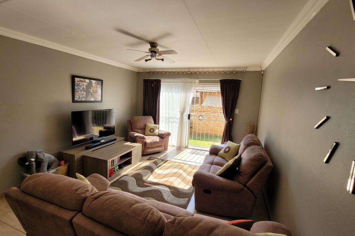 A comfortable living room featuring tiled flooring, a ceiling fan, and a sliding glass door providing access to the outdoor area.