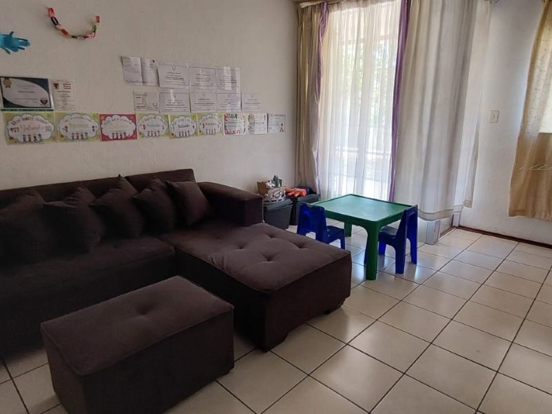A functional living room featuring tiled flooring and a sliding glass door providing access to the exterior, offering a bright and practical living space.