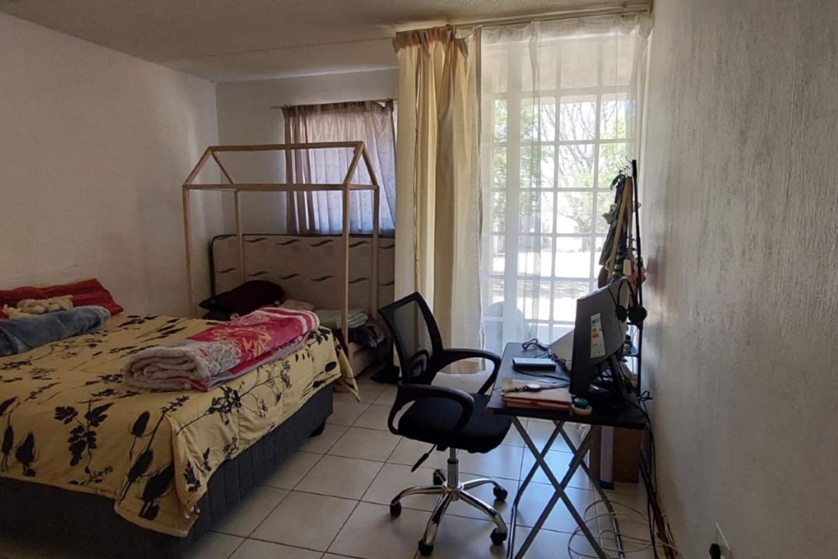 A bedroom featuring tiled flooring and a glass sliding door providing natural light and access to the exterior.