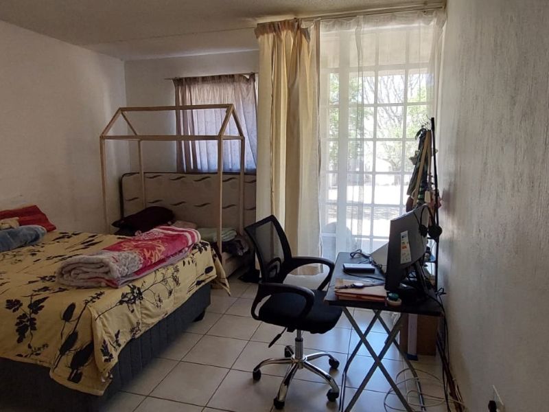 A bedroom featuring tiled flooring and a glass sliding door providing natural light and access to the exterior.