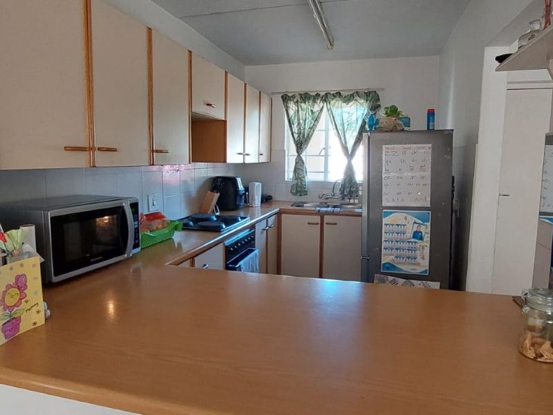 A functional kitchen featuring laminate countertops, built-in cabinetry, a tiled backsplash, and integrated cooking appliances, offering a practical layout for daily use.