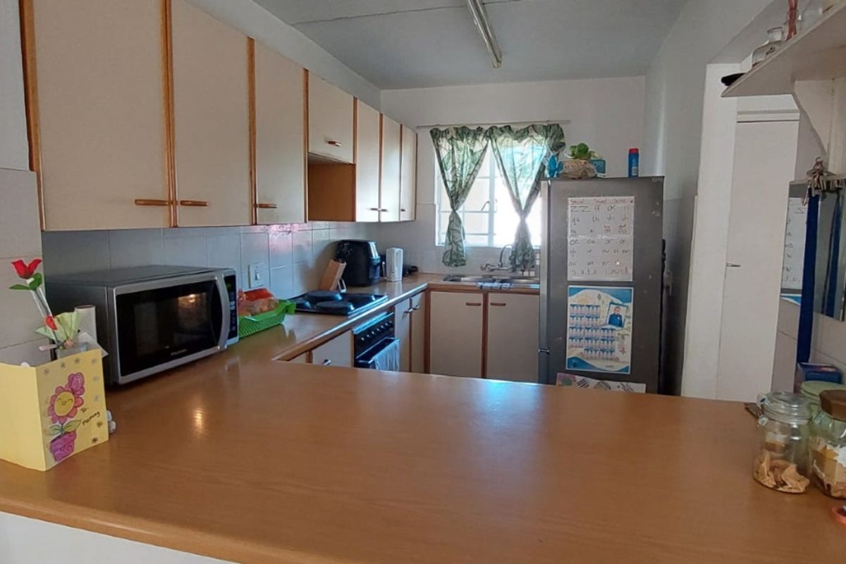 A functional kitchen featuring laminate countertops, built-in cabinetry, a tiled backsplash, and integrated cooking appliances, offering a practical layout for daily use.