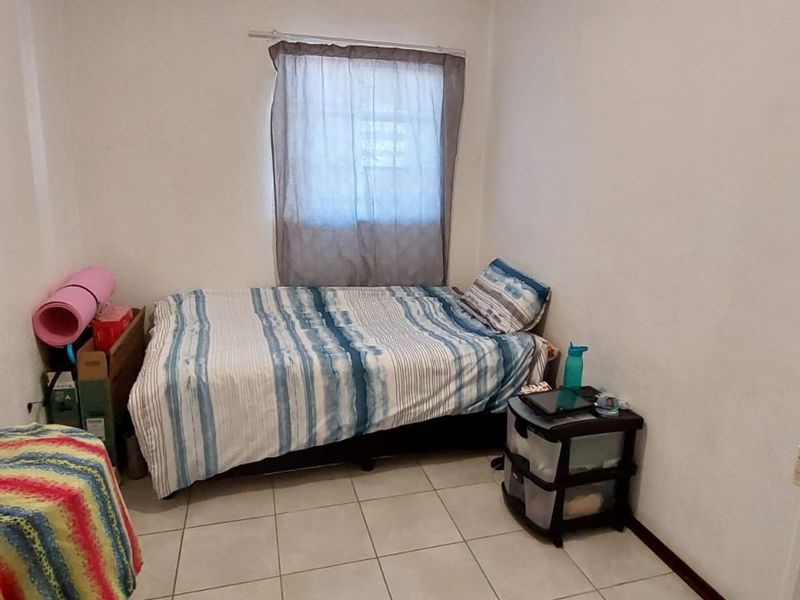 A compact bedroom featuring tiled flooring and a single window, providing a functional space ready for personalization.