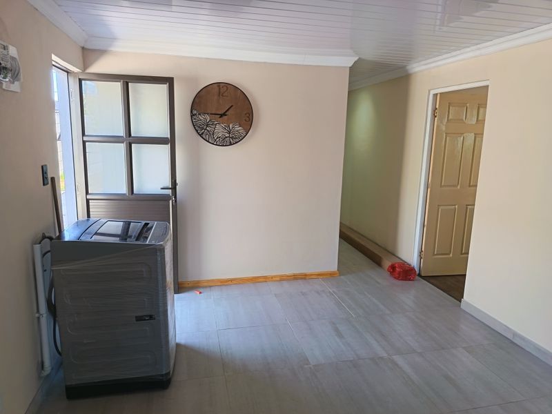 A functional laundry area featuring tiled flooring, a panelled ceiling, and direct access to the exterior.