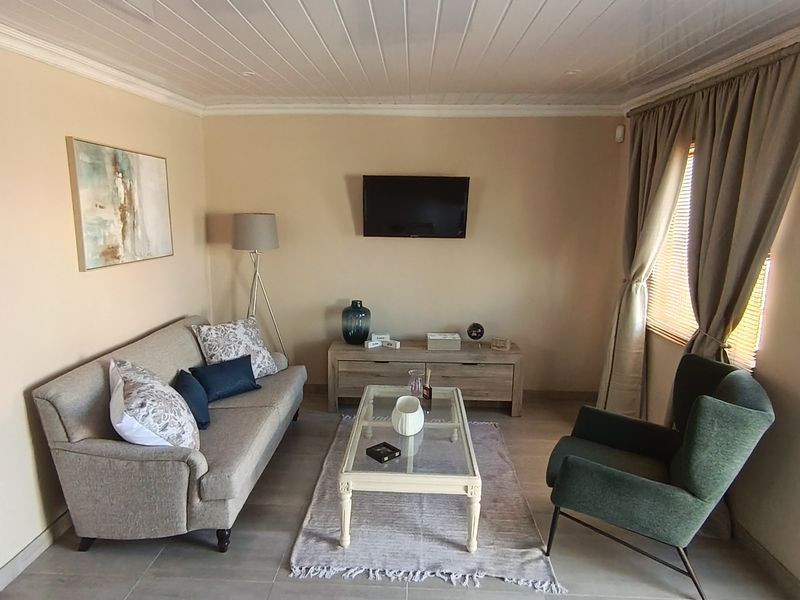 A well-maintained living room featuring neutral tiled flooring and a white tongue and groove ceiling, offering a comfortable and functional space.