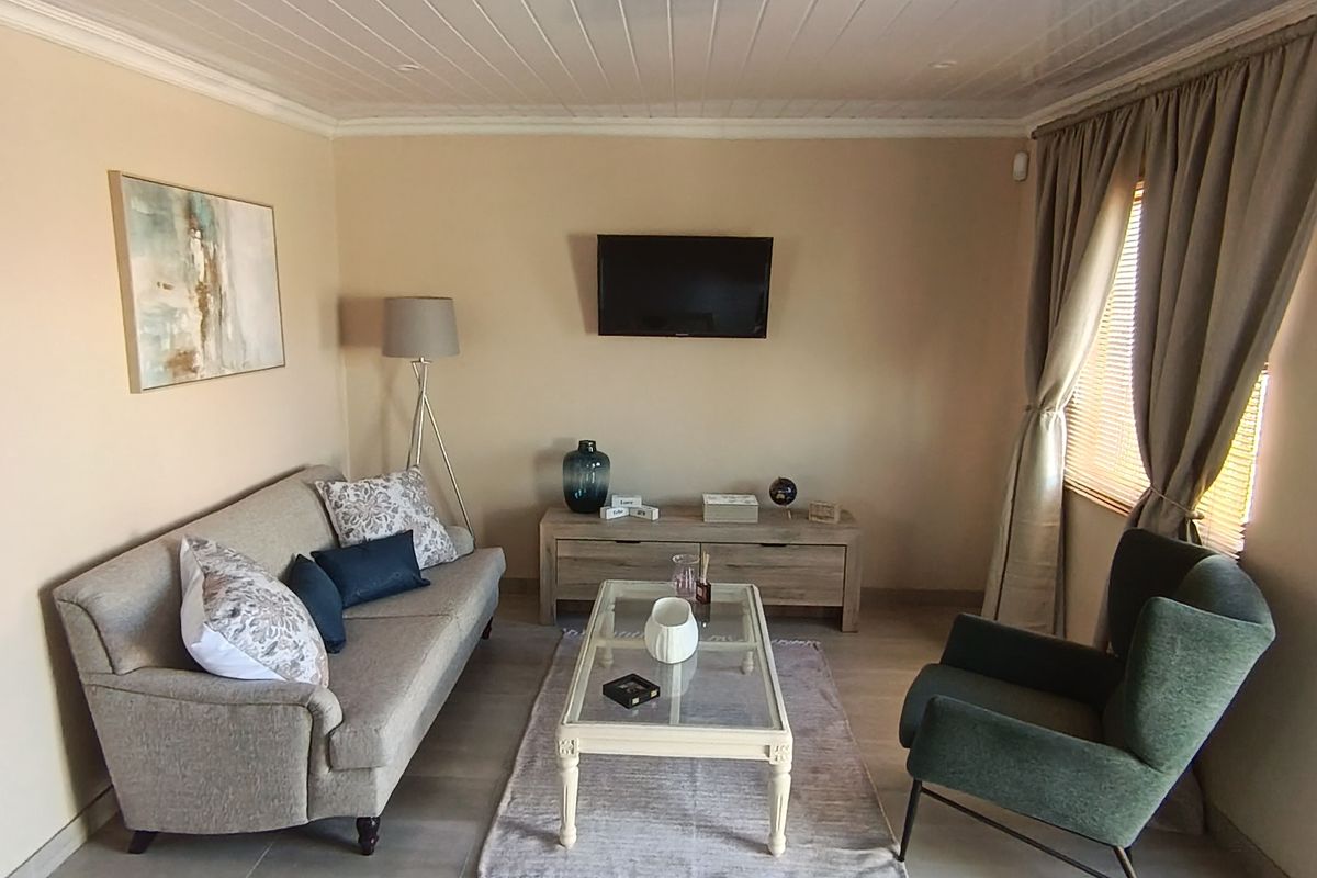 A well-maintained living room featuring neutral tiled flooring and a white tongue and groove ceiling, offering a comfortable and functional space.