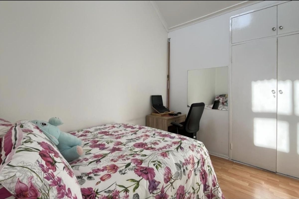 A bedroom featuring laminate flooring, a vaulted ceiling, and a built-in wardrobe with white doors.
