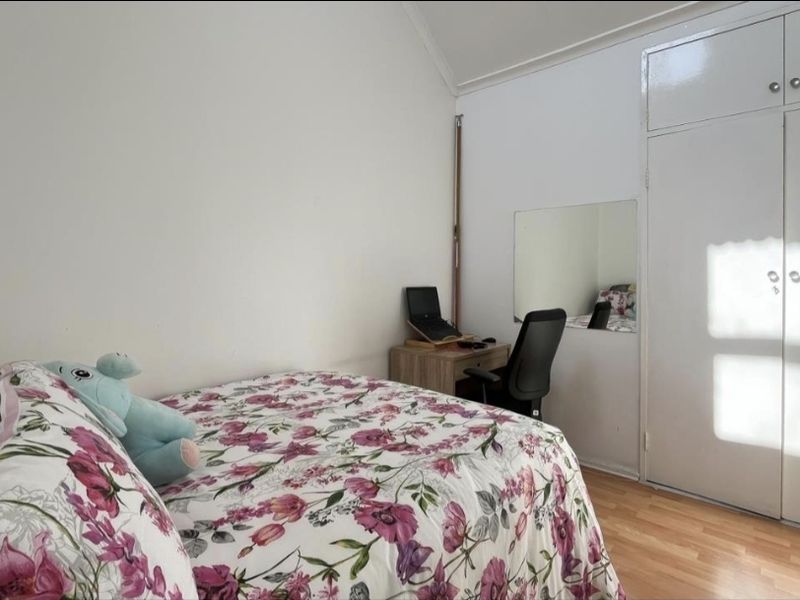 A bedroom featuring laminate flooring, a vaulted ceiling, and a built-in wardrobe with white doors.