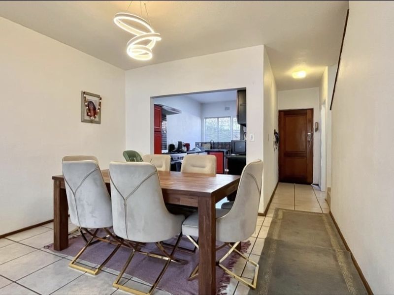 Open plan dining area featuring tiled flooring and a modern pendant light, with a convenient pass-through opening to the kitchen.