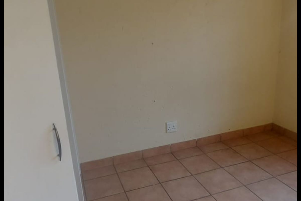 An empty bedroom featuring ceramic floor tiles and a built-in cupboard, providing a blank canvas for personalization.