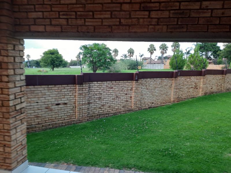 A covered patio area overlooking a private garden with a brick boundary wall and installed electric fencing.