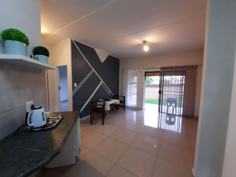 Open-plan living area featuring tiled flooring, a modern accent wall, and a sliding glass door providing access to the outdoor patio area.