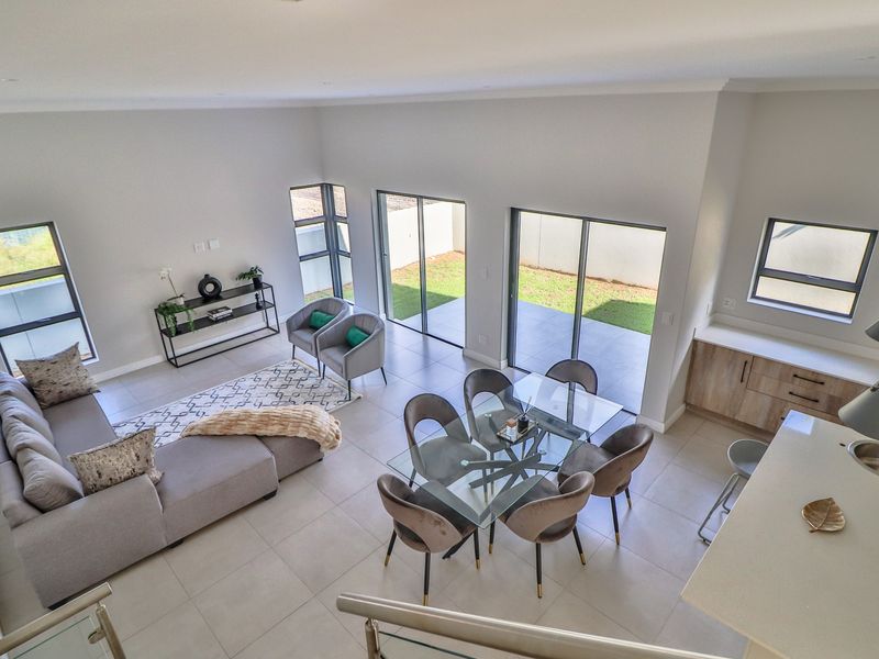 Spacious open-plan living and dining area featuring modern tiled floors, large sliding glass doors leading to the garden, and a contemporary kitchen.