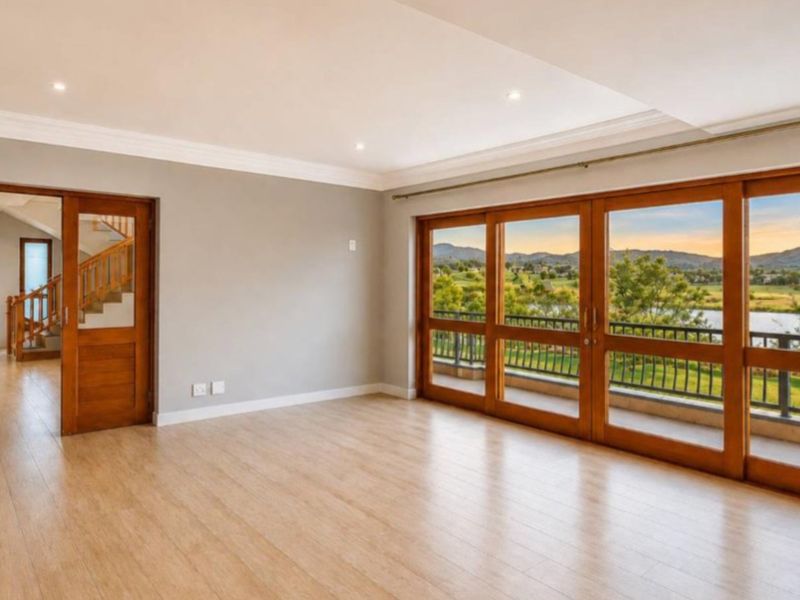 Spacious living area featuring timber flooring, recessed lighting, and large sliding doors opening onto a balcony with scenic views.