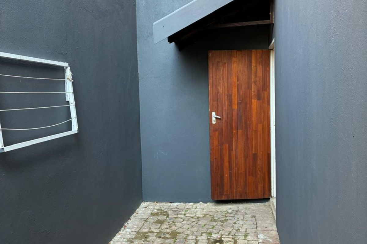 A private rear courtyard area featuring cobblestone paving, a timber entrance door, and a protective awning.