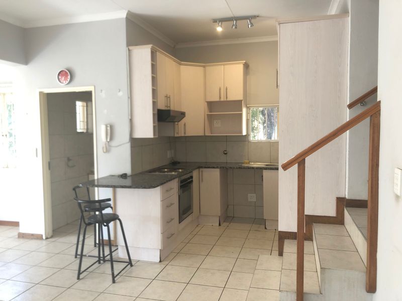 Functional kitchen featuring built-in cabinetry, granite countertops, and an integrated oven, adjacent to a staircase with a wooden handrail.