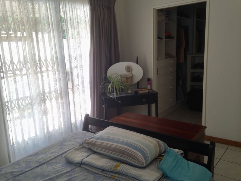 Bedroom featuring tiled flooring, a sliding door with curtains, and an adjoining walk-in closet with built-in cabinetry.