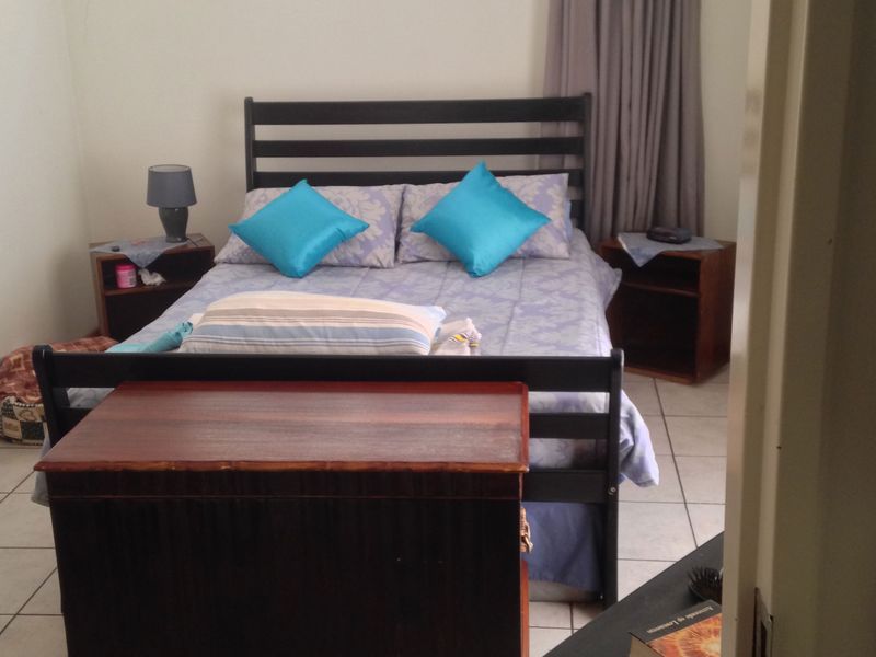 A functional bedroom featuring tiled flooring and a window with a curtain rail, offering a neutral base for personalization.