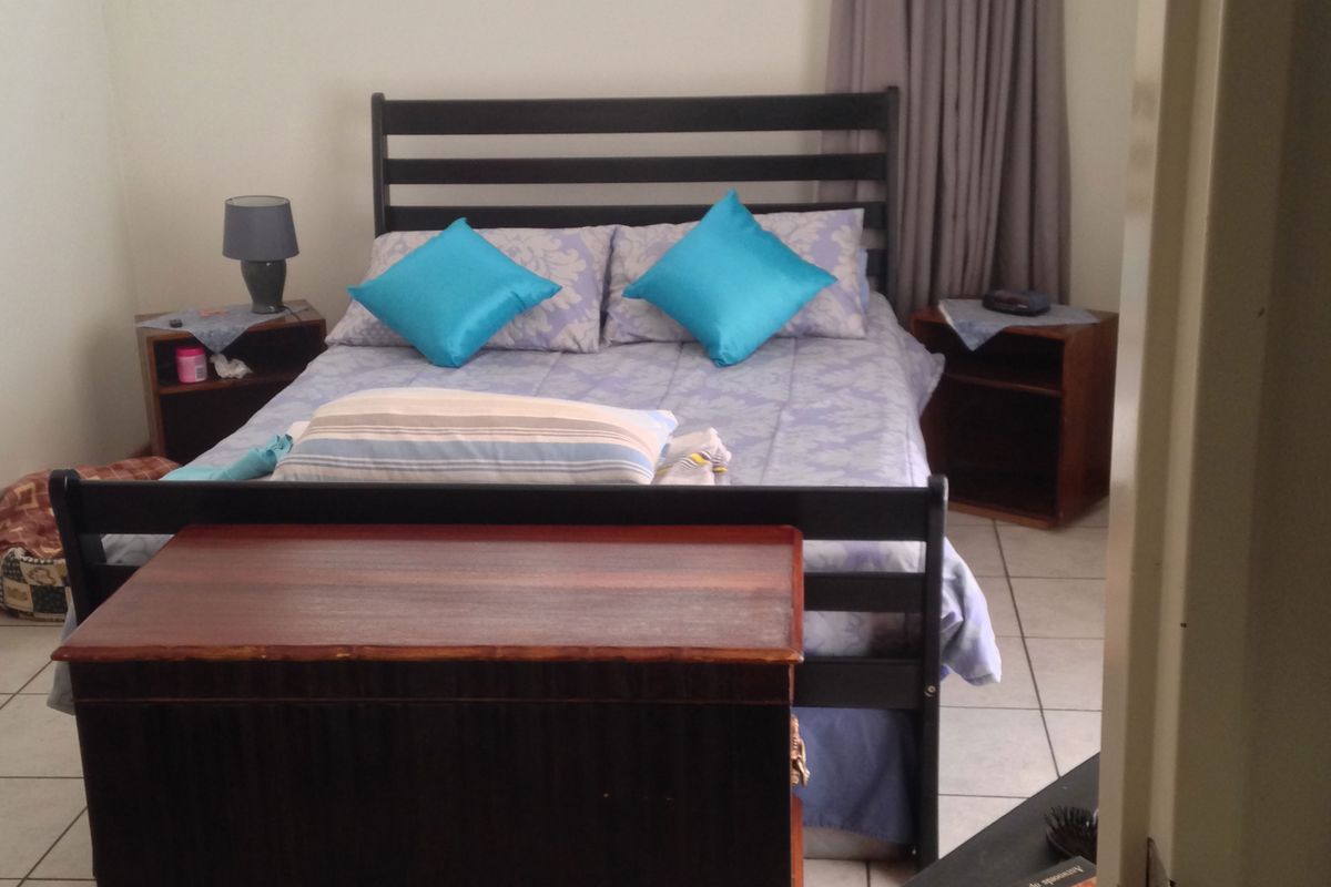A functional bedroom featuring tiled flooring and a window with a curtain rail, offering a neutral base for personalization.