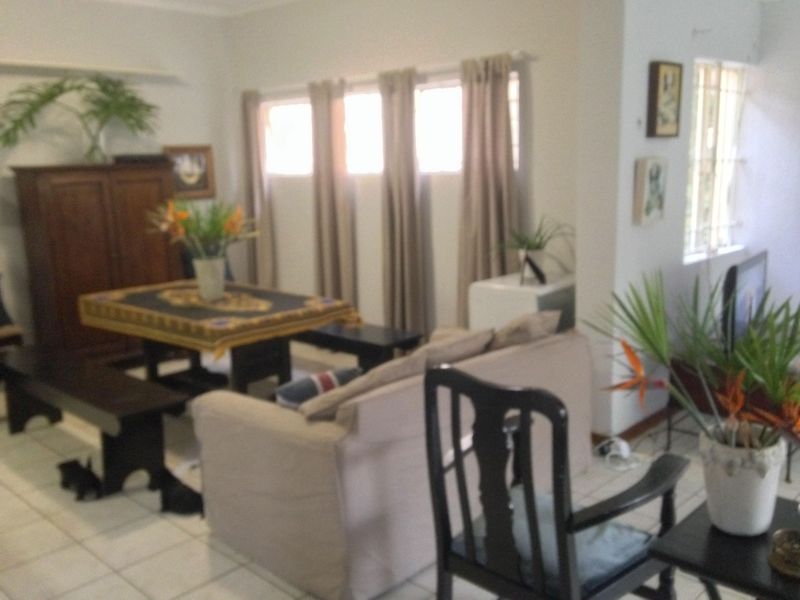 A living room area featuring tiled flooring and windows fitted with security bars.