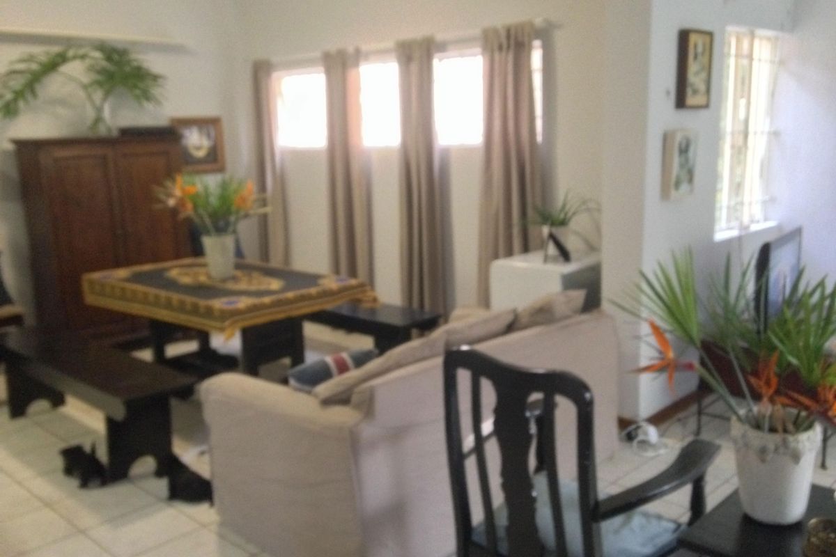 A living room area featuring tiled flooring and windows fitted with security bars.