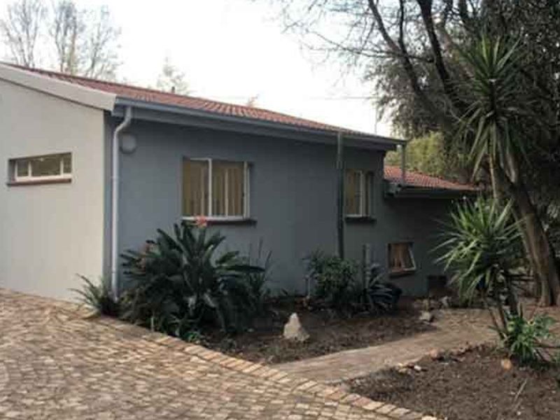 Front exterior view of the house featuring a paved driveway, tiled roof, and established garden surroundings.